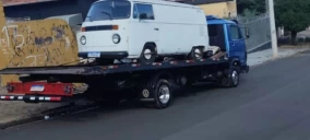 Guincho plataforma estacionado na rua em Francisco Morato, transportando uma van branca.