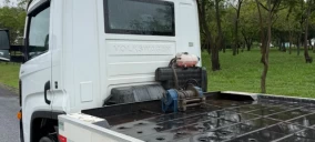 Guincho tipo plataforma estacionado em Assis, com motor visível na parte traseira e fundo plano.