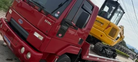 Guincho plataforma vermelho transportando uma escavadeira amarela em Videira, SC.