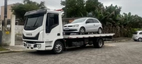 Guincho plataforma em Balneário Camboriú transportando um carro prata sobre a carroceria.