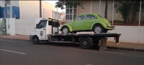 Guincho plataforma estacionado na rua em Franco da Rocha, transportando um carro verde, modelo fusca.