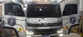 Caminhão guincho com portas abertas, estacionado em local coberto, com adesivos visíveis na carroceria.