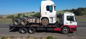 Guincho plataforma transportando um caminhão branco na rodovia em São Bernardo do Campo.