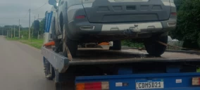 Guincho plataforma transportando um veículo cinza na rua em Novo Gama.