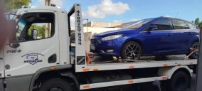 Guincho plataforma transportando um carro azul, modelo Ford, em São José dos Pinhais.