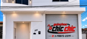 Imagem de um prédio com fachada branca e uma porta de enrolar cinza, localizado em Delmiro Gouveia.