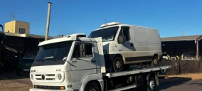 Guincho plataforma em Bauru transportando uma van branca, estacionado em área externa.