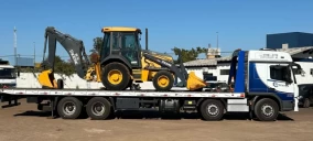 Guincho plataforma transportando uma retroescavadeira amarela em Campo Grande.