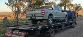 Guincho plataforma transportando uma caminhonete Ford F-150 em estrada rural em Alegrete, RS.