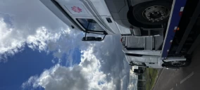 Guincho tipo plataforma estacionado em avenida, com caminhão visível em Alegrete.