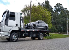 Guincho plataforma em Caxias do Sul transportando um carro cinza.