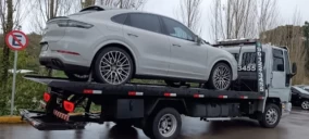 Guincho plataforma transportando um veículo branco, estacionado em Caxias do Sul.
