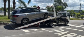 Guincho plataforma em Caxias do Sul transportando um veículo SUV prata estacionado na rua.