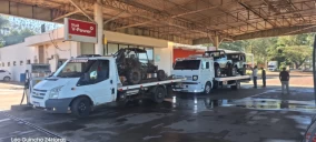 Dois guinchos de plataforma brancos estão estacionados em um posto de combustível em Piraju, um deles transporta um veículo off-road.