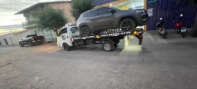 Guincho plataforma transportando um SUV cinza em Juazeiro do Norte, estacionado em uma rua.