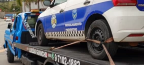 Guincho plataforma transportando veículo da polícia, estacionado em São Roque, com cordas de amarração visíveis.