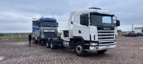 Guincho de plataforma branco em Cascavel, transportando caminhão azul estacionado em área pavimentada.