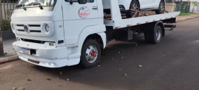 Guincho plataforma branco estacionado na rua em Ibema, transportando um carro de passeio.