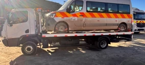 Guincho plataforma transportando uma van com faixas laranjas e amarelas em Paracambi.