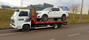 Guincho plataforma estacionado na rua, transportando uma caminhonete branca em Carazinho.