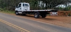 Guincho plataforma estacionado em estrada de terra em Utinga, sem veículo transportado visível.