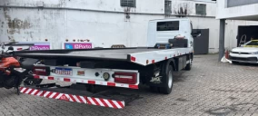 Guincho plataforma estacionado em área pavimentada, com veículo branco visível ao fundo em Belém.