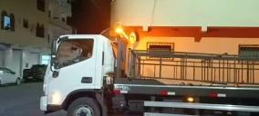 Guincho de plataforma branco estacionado em Itapetinga, com estrutura metálica visível na parte traseira.