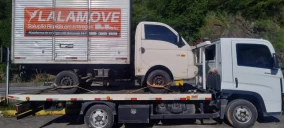 Guincho plataforma em Japeri transportando caminhão branco com cabine visível e carroceria fechada.