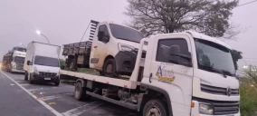 Guincho plataforma transportando uma caminhonete branca em Japeri, estacionado à beira da estrada.