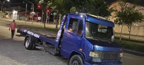 Guincho plataforma azul estacionado em Viana, com um homem ao fundo e sem veículo transportado.