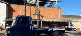 Guincho plataforma azul estacionado em área com paredes de tijolos à vista, em Viana.