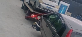 Guincho plataforma em Itaquaquecetuba transportando um veículo branco e um cinza, ambos estacionados.