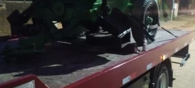 Guincho plataforma transportando um veículo verde em Córrego Danta, estacionado em via pública.