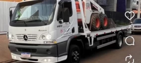 Guincho plataforma estacionado em Indaiatuba, transportando uma máquina com pneus grandes.
