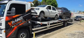 Guincho plataforma em Teresina transportando um carro branco e um SUV cinza, estacionado em uma rua.